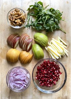 an assortment of fruits and vegetables sitting on a table top next to bowls with nuts