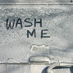 the words wash me are written in black ink on an old metal box that has been vandalized