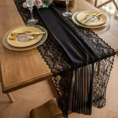 the table is set with black lace and gold place settings for two people to sit at