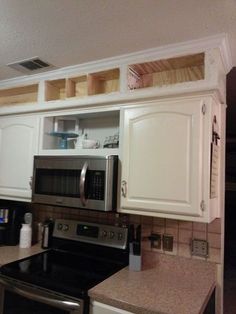 a kitchen with white cabinets and stainless steel stove top oven in the corner, next to an open microwave