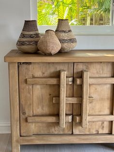 two vases sitting on top of a wooden cabinet