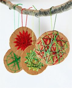 three ornaments hanging from a tree branch on a white background with green and red thread