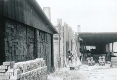 an old black and white photo of people standing in front of a building with brick walls