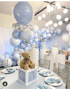 a teddy bear sitting on top of a table in front of balloons and other decorations