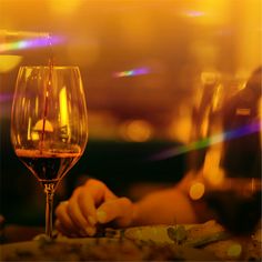 a person sitting at a table with a glass of wine in front of them,