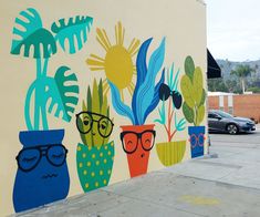 a colorful mural on the side of a building with potted plants painted on it