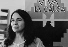 a black and white photo of a woman standing in front of a sign that says viva la causa