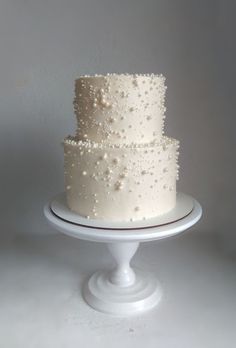 a three tiered white cake with pearls on it