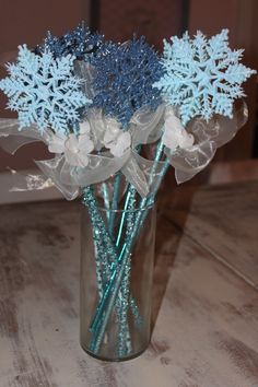 a vase filled with blue and white snowflakes on top of a wooden table