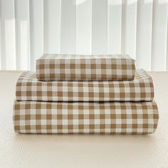 two brown and white checkered sheets sitting on top of each other in front of a window