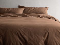 a bed with brown sheets and pillows in a room