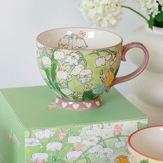 two cups on top of each other with flowers in the background