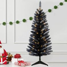 a small christmas tree sitting next to a santa clause figure and presents on a table