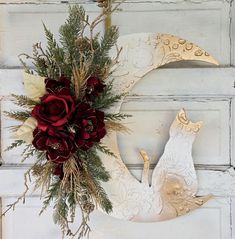 a white wreath with red flowers and a bird decoration on the front of a door