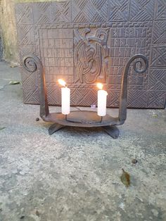 two lit candles sitting on top of a metal stand