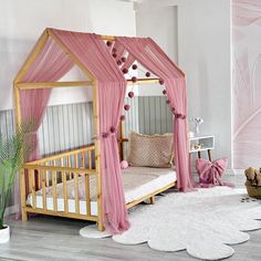 a pink canopy bed in a girls room with white rugs and wooden flooring