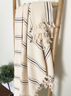 a white and black striped towel hanging on a ladder next to a potted plant