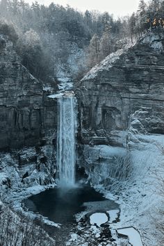 a large waterfall is surrounded by snow and ice