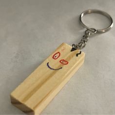 a wooden keychain with a smiley face drawn on it