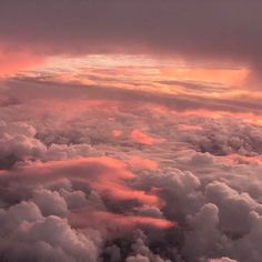 the sky is filled with clouds as the sun goes down in the distance and it appears to be pink