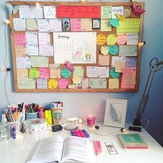 an open book sitting on top of a desk next to a wall mounted bulletin board