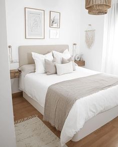 a bed with white linens and pillows in a bedroom next to two pictures on the wall