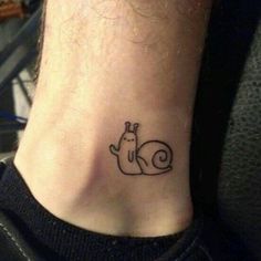 a small tattoo on the ankle of a person with a snail in it's shell