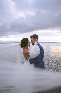 a bride and groom embracing on the beach