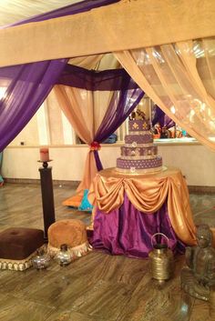 a wedding cake sitting on top of a table covered in purple and gold cloths