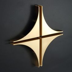 a wall mounted clock on the side of a black wall with two intersecting pieces in it