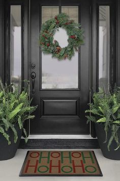 the front door is decorated for christmas with wreaths and evergreen leaves on it's mat