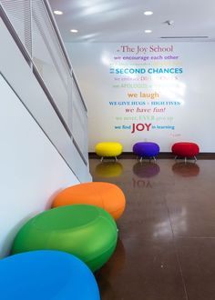 brightly colored chairs are lined up in front of a wall that reads the joy school