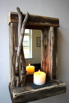 two candles are sitting on a shelf in front of a mirror that is made out of driftwood