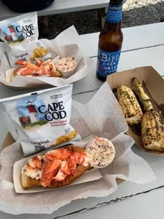 two hot dogs and corn on the cob with cape food in paper wrappers