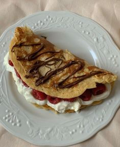 a white plate topped with a pastry covered in whipped cream and strawberries on top of it