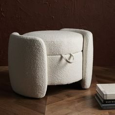 a white chair sitting on top of a wooden floor next to a stack of books