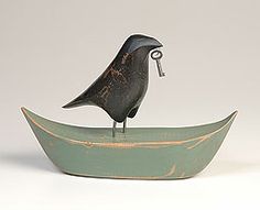 a bird figurine sitting on top of a green boat with a key in it's mouth