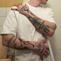 a man with tattoos on his arms and shoulder standing in front of a bathroom mirror