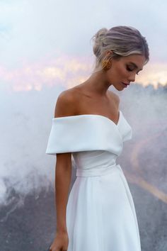 a woman in a white dress is holding an umbrella and looking down at the ground