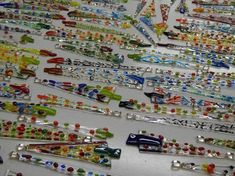 many different colored and shaped glass beads on a white table with other items in the background