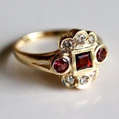 A semi-circle of diamonds totaling 0.25 carats flanks ruby-red garnets. Surely a heirloom piece to be cherished for generations. Ring size ranges from 5-8. Antique Style Jewelry, Garnet And Diamond Ring, Replica Jewelry, Garnet Jewelry, St Nicholas, Garnet Rings, Gems Jewelry, Hand Made Jewelry, Ring Collections