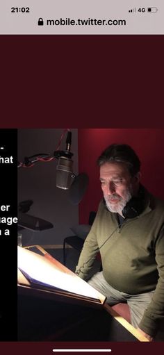 a man sitting in front of a book on top of a table next to a microphone