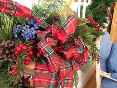 a christmas wreath with pine cones, berries and evergreens tied to it on a chair