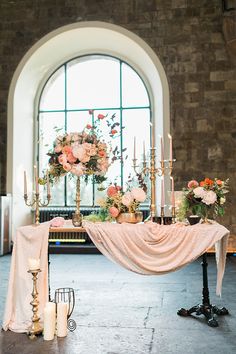 a table with candles and flowers on it in front of a large window at a wedding