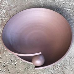 a brown bowl with an egg in it on the ground next to a gray object