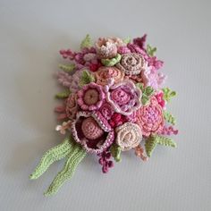 a crocheted bridal bouquet with pink and green flowers on a white surface