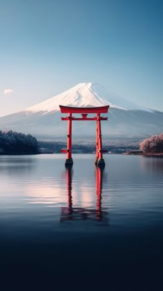 a large body of water next to a mountain with a red gate on it's side