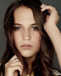 a close up of a person with long hair and wearing a ring on her finger