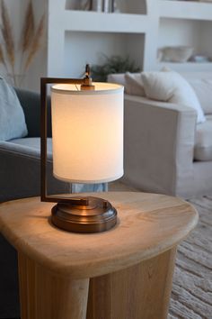 a table lamp sitting on top of a wooden table in front of a living room