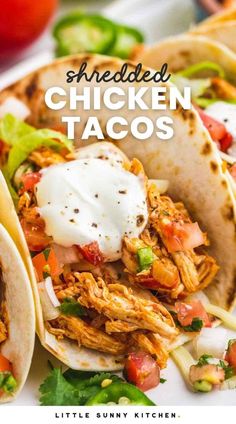 shredded chicken tacos on a white plate with tomatoes and lettuce in the background